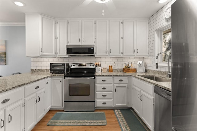 kitchen with sink, light hardwood / wood-style flooring, ornamental molding, white cabinetry, and stainless steel appliances