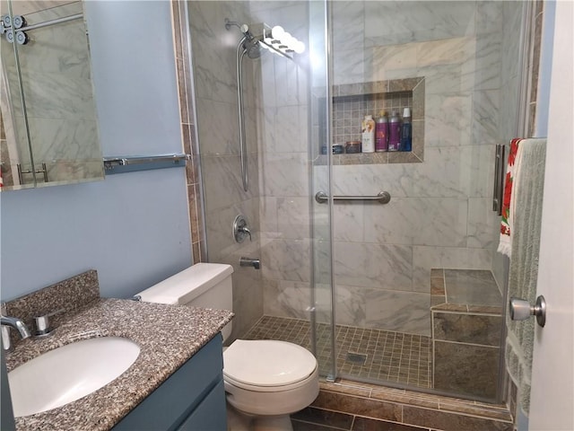 bathroom with tile patterned floors, vanity, toilet, and a shower with shower door