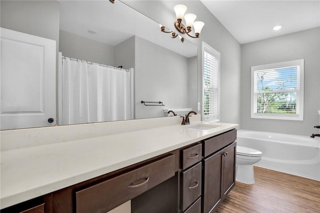 bathroom featuring a bathtub, vanity, wood-type flooring, a notable chandelier, and toilet