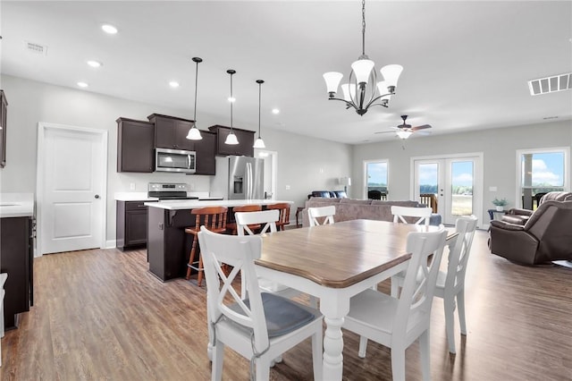 dining room with french doors, light hardwood / wood-style flooring, and ceiling fan with notable chandelier