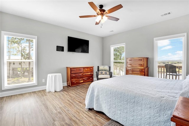 bedroom with multiple windows, light hardwood / wood-style floors, and ceiling fan