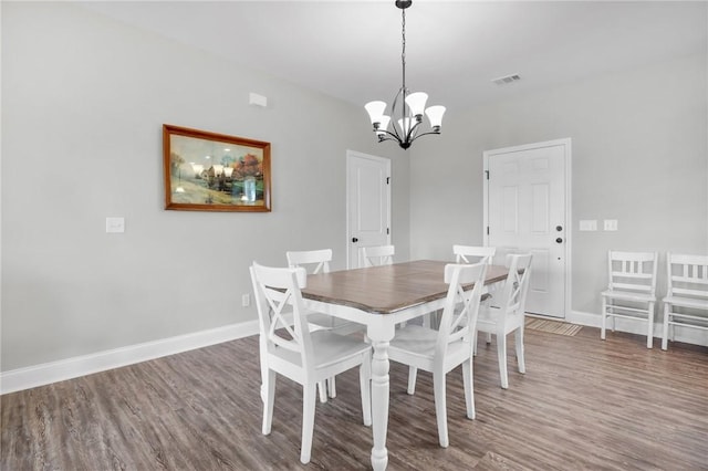 dining area with dark hardwood / wood-style floors and a notable chandelier