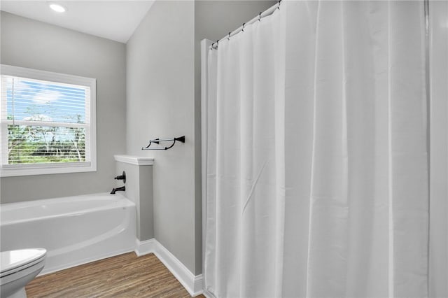 bathroom with wood-type flooring, toilet, and a tub