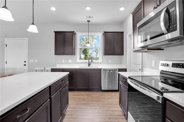 kitchen featuring dark brown cabinets, sink, decorative light fixtures, and appliances with stainless steel finishes