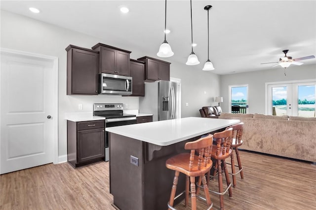 kitchen with a kitchen bar, french doors, dark brown cabinets, stainless steel appliances, and pendant lighting