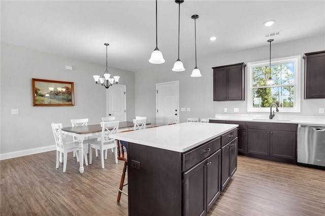 kitchen featuring sink, stainless steel dishwasher, light hardwood / wood-style floors, decorative light fixtures, and a kitchen island