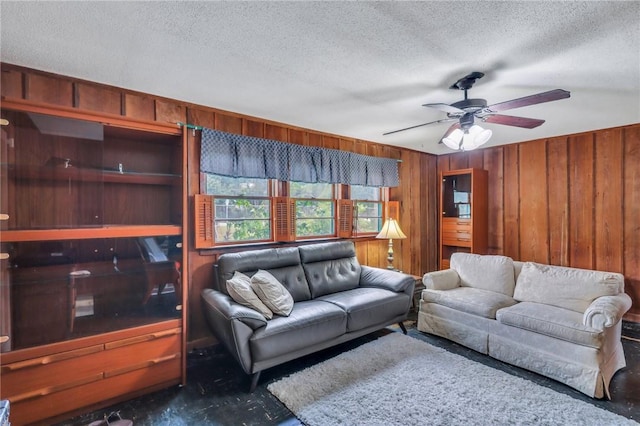 living room with a textured ceiling, ceiling fan, and wooden walls