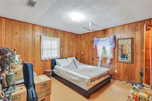 bedroom featuring ceiling fan, wooden walls, light colored carpet, and a textured ceiling