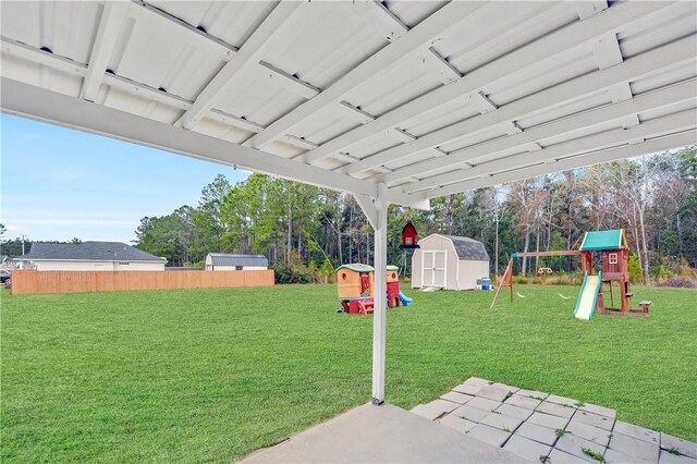 view of yard featuring a patio, a playground, and a storage shed