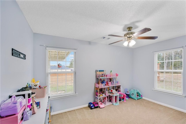 recreation room with ceiling fan, a wealth of natural light, and carpet