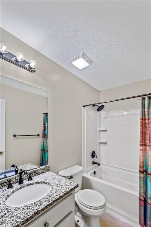 full bathroom with a textured ceiling, tile patterned flooring, vanity, toilet, and shower / tub combo with curtain