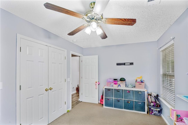 playroom featuring light carpet, a textured ceiling, and ceiling fan