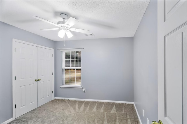 unfurnished bedroom with a textured ceiling, carpet flooring, and ceiling fan