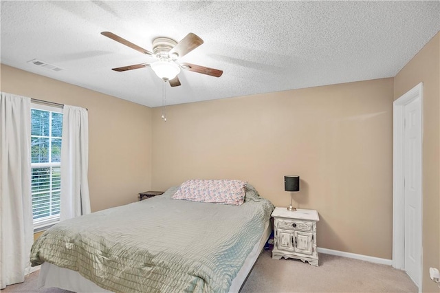 carpeted bedroom featuring ceiling fan and a textured ceiling