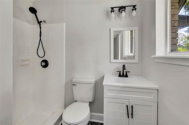 bathroom featuring a tile shower, vanity, and toilet