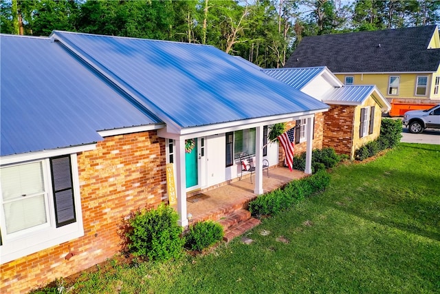 1622 Booth St, Waycross, GA 31501 - rear view of property featuring a lawn, a porch, brick siding, and metal roof