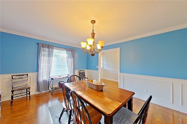 1622 Booth St, Waycross, GA 31501 - dining space featuring a wainscoted wall, a chandelier, ornamental molding, light wood-style flooring, and a decorative wall
