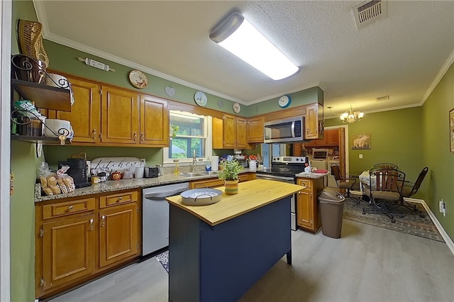 1622 Booth St, Waycross, GA 31501 - kitchen featuring appliances with stainless steel finishes, light wood finished floors, a sink, wood counters, and crown molding