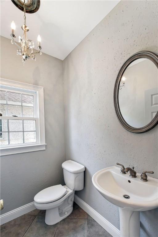 bathroom with tile patterned flooring, a chandelier, and toilet