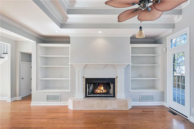 unfurnished living room with a high end fireplace, ceiling fan, built in features, ornamental molding, and wood-type flooring