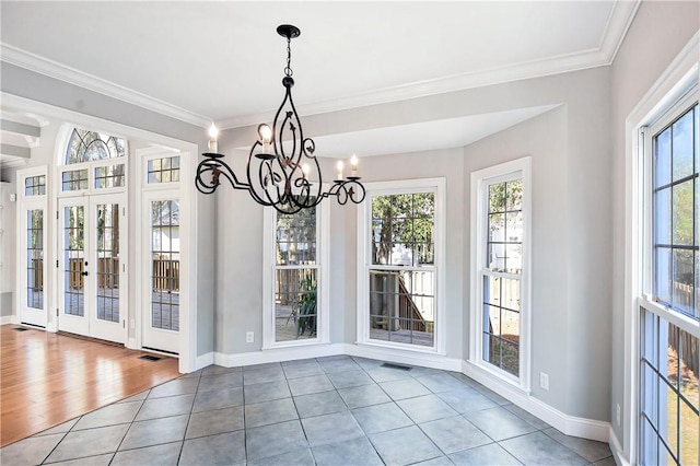 unfurnished dining area with plenty of natural light, wood-type flooring, french doors, and an inviting chandelier