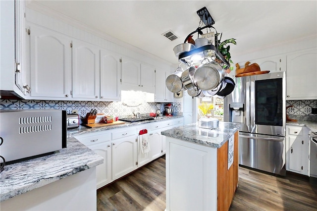 kitchen with white cabinetry, a center island, light stone counters, stainless steel appliances, and dark wood-type flooring