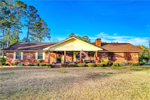 ranch-style house featuring covered porch and a front lawn