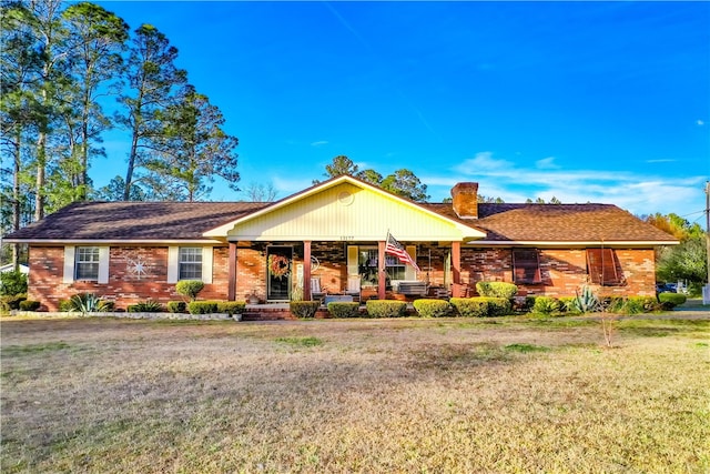 ranch-style house featuring covered porch and a front lawn