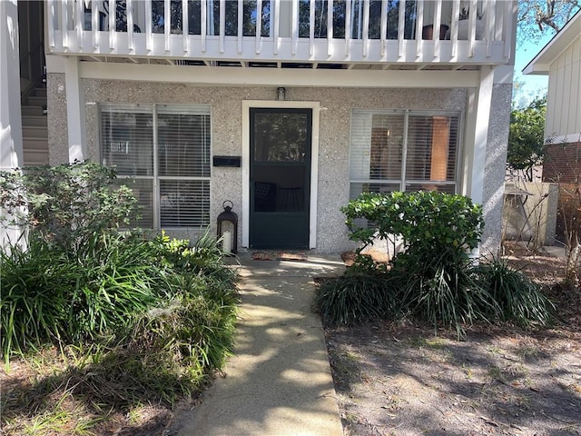 view of exterior entry featuring a balcony and stucco siding