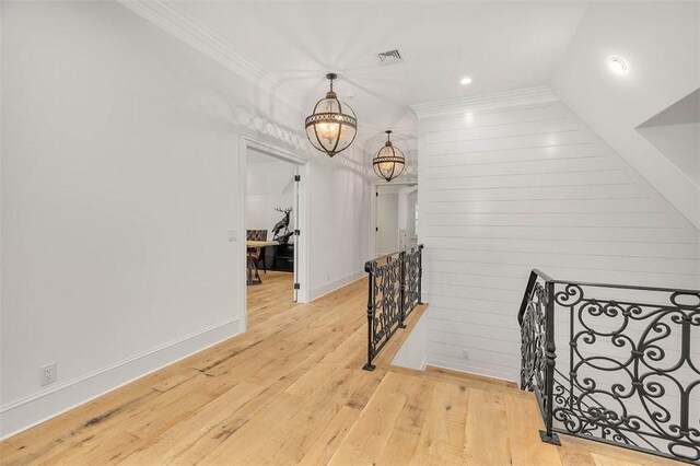 hall featuring crown molding, light hardwood / wood-style flooring, wood walls, and lofted ceiling