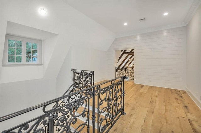 corridor with lofted ceiling, crown molding, and light hardwood / wood-style flooring