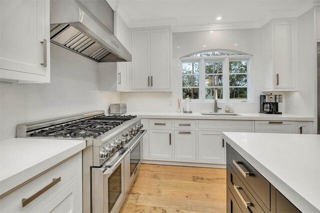 kitchen featuring white cabinetry, wall chimney exhaust hood, and double oven range