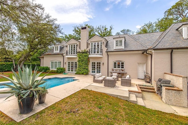 back of house featuring an outdoor living space, french doors, a balcony, exterior kitchen, and a patio