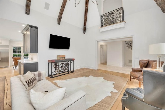 living room featuring beam ceiling, light wood-type flooring, and high vaulted ceiling