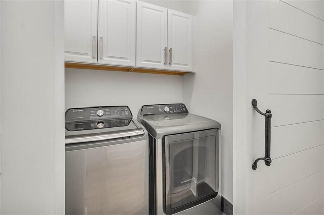 washroom with washing machine and clothes dryer and cabinets