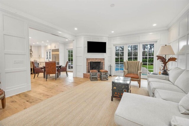 living room with a fireplace, light wood-type flooring, and crown molding