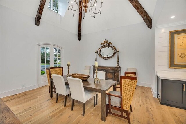 dining area with a chandelier, beam ceiling, light hardwood / wood-style flooring, and french doors