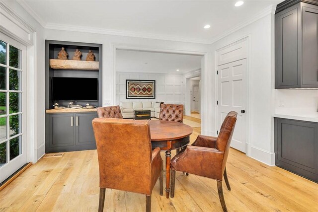 dining space with light wood-type flooring and crown molding