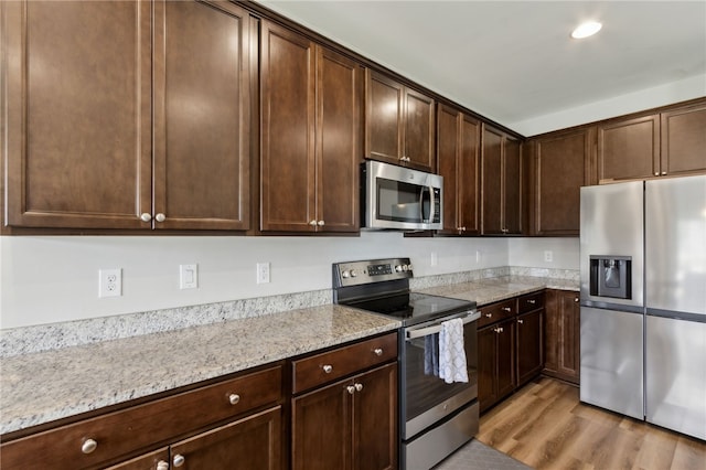 259 Daniel Trent Way, Kingsland, GA 31548 - kitchen with appliances with stainless steel finishes, dark brown cabinets, light wood finished floors, and light stone counters