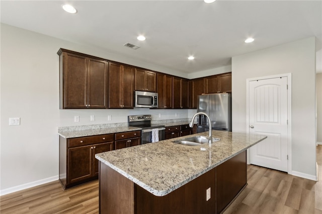 259 Daniel Trent Way, Kingsland, GA 31548 - kitchen featuring appliances with stainless steel finishes, light wood-style floors, dark brown cabinets, light stone countertops, and recessed lighting
