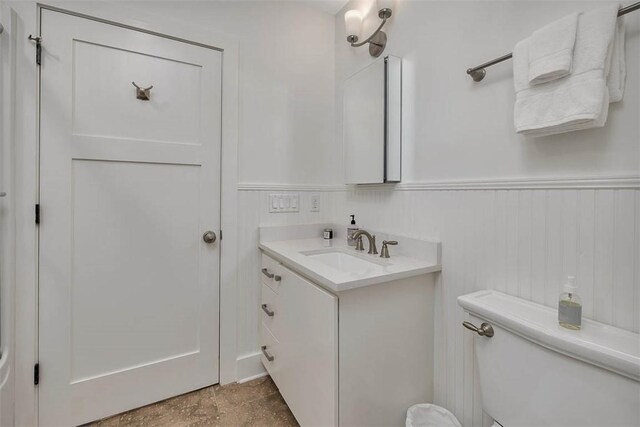 half bath featuring toilet, a wainscoted wall, and vanity