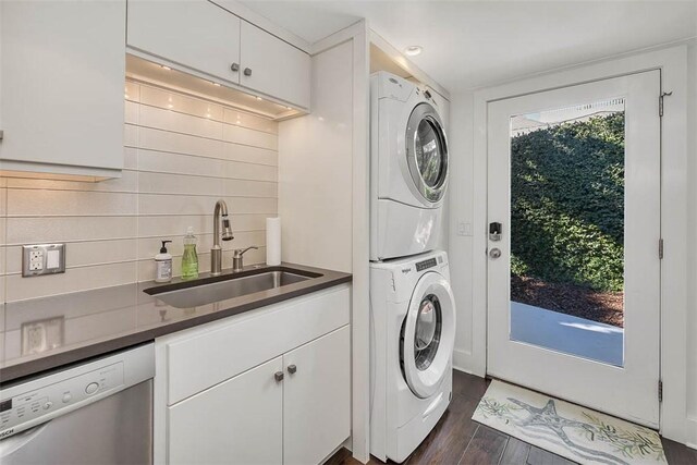 laundry area featuring dark wood-type flooring, stacked washer / dryer, a sink, and cabinet space