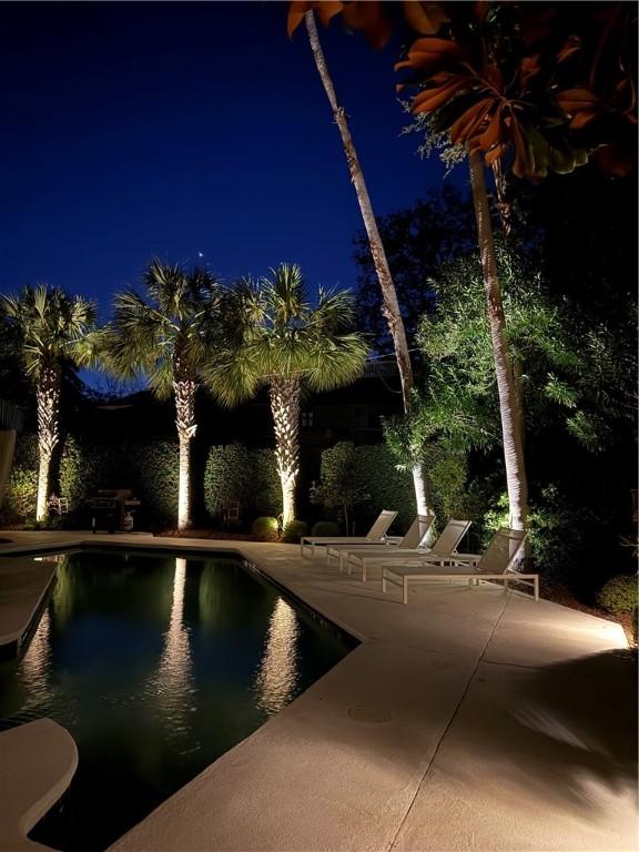 pool at twilight with a patio area and an outdoor pool