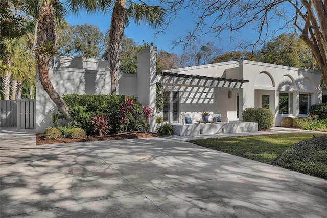 view of front of property with a chimney, fence, and stucco siding