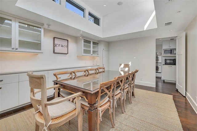 dining space with dark wood finished floors, visible vents, and baseboards