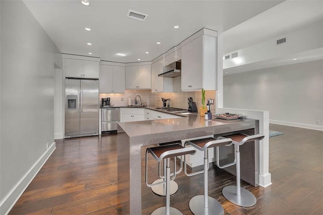 kitchen with appliances with stainless steel finishes, dark wood-type flooring, visible vents, and decorative backsplash