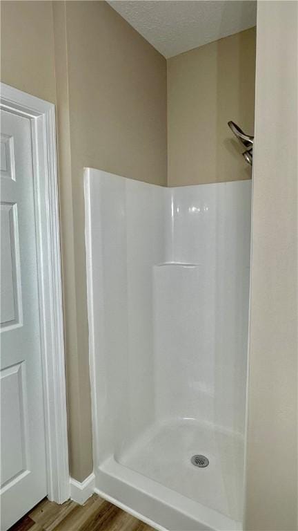 bathroom featuring wood-type flooring, a textured ceiling, and walk in shower