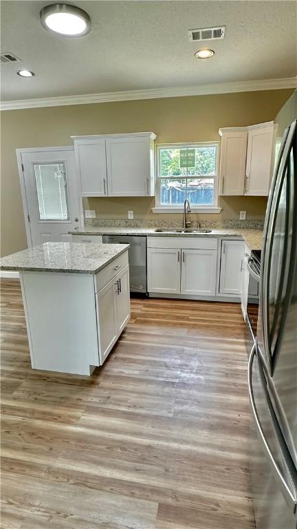 kitchen with a kitchen island, white cabinetry, sink, and stainless steel appliances