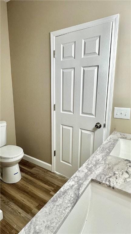 bathroom with toilet, vanity, and hardwood / wood-style flooring