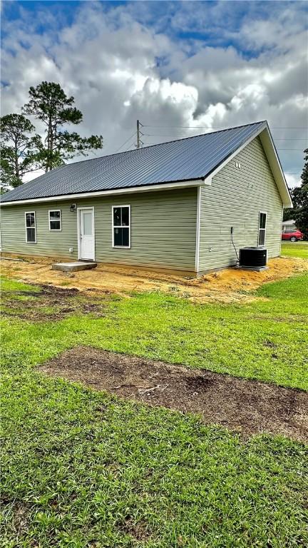 back of property with a yard and central AC